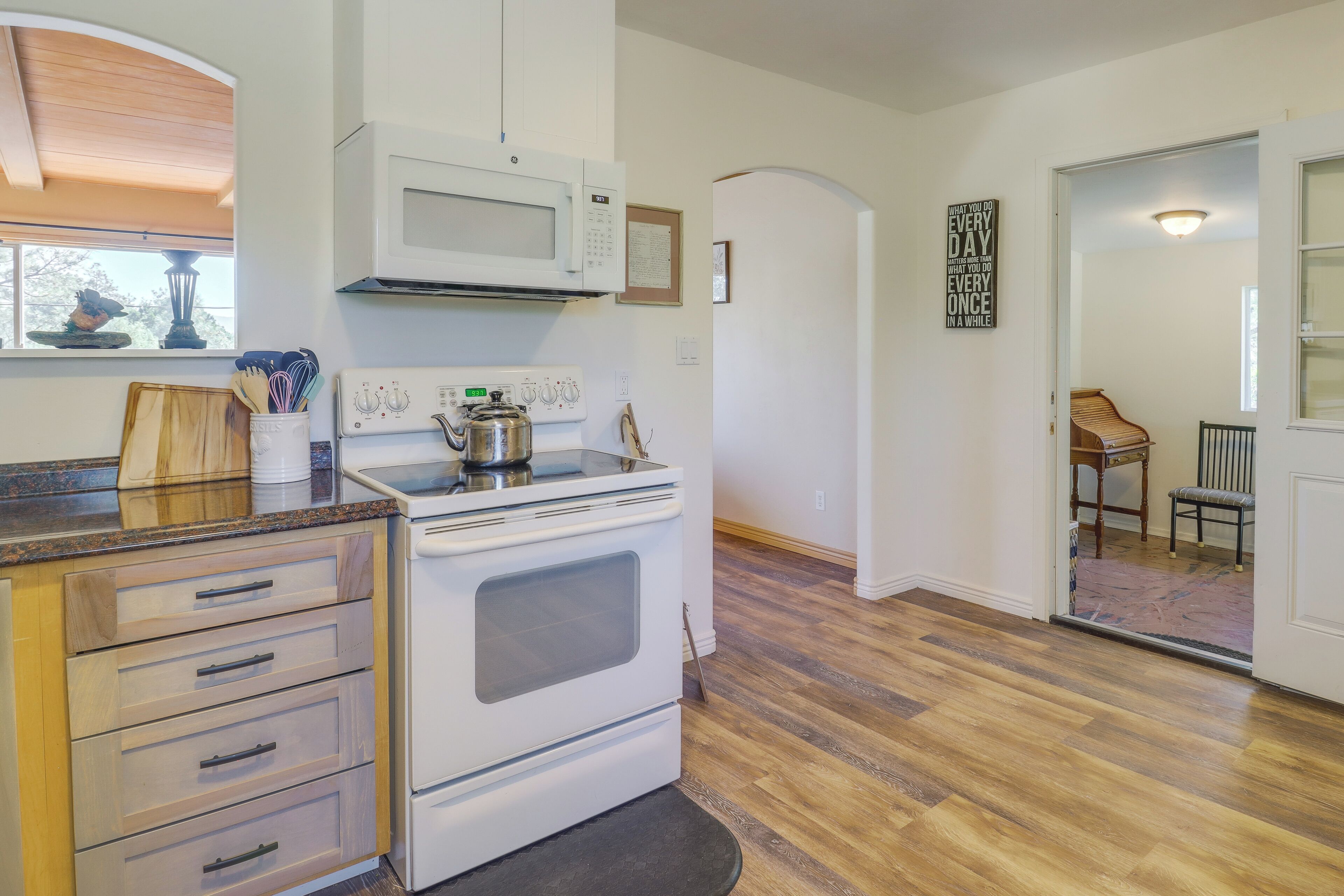 Une cuisine équipée d’une cuisinière, d’un four à micro-ondes et de meubles de rangement en bois.