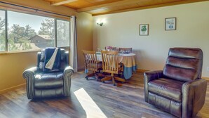 A room with two leather chairs, a dining table with chairs, wooden flooring, a window with a view of trees, and wall-mounted lights. - 2 Mi to Dtwn: Prescott Gem w/ Patio & Views! (Prescott)