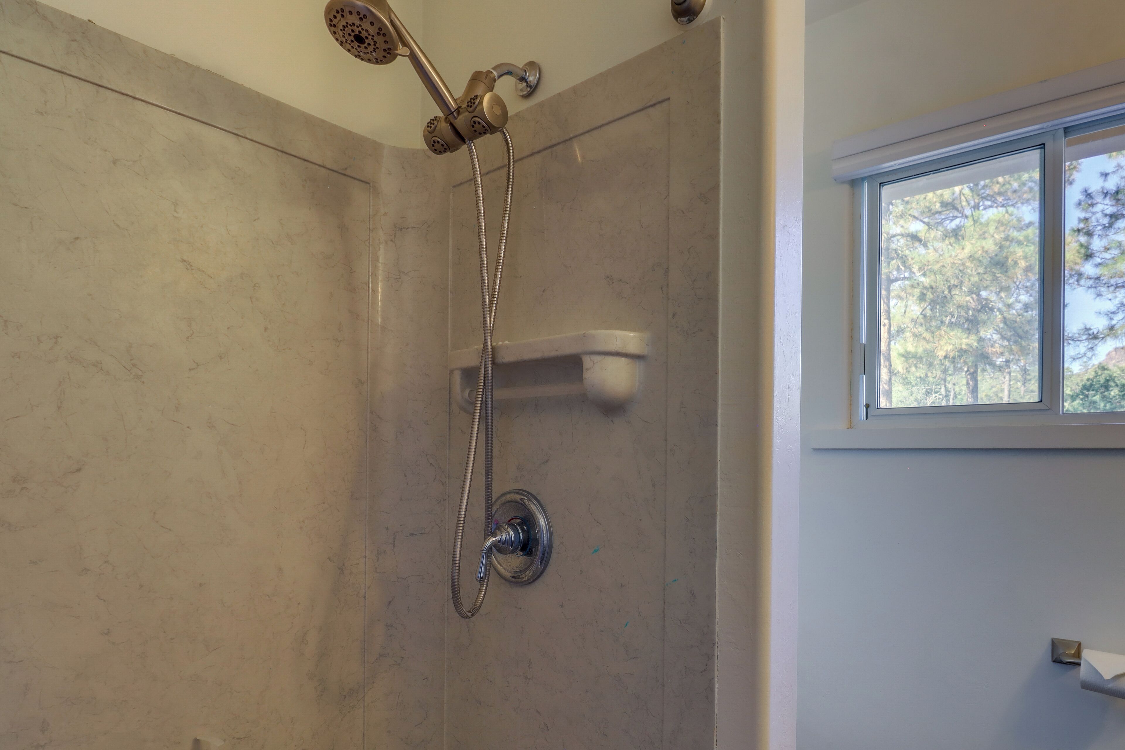 A shower with a handheld showerhead and a wall-mounted faucet.