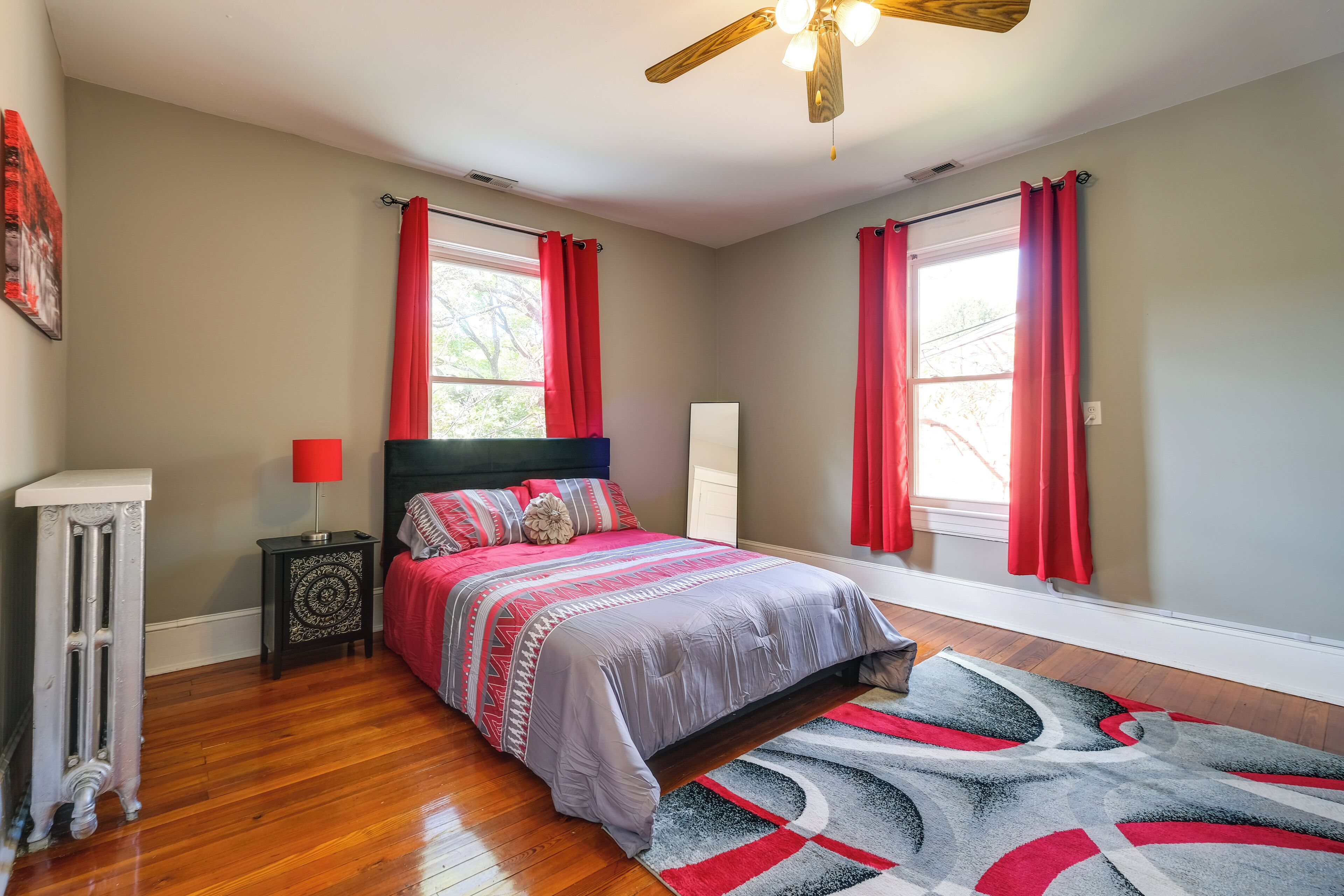 Une chambre à coucher avec un lit, une table de chevet, un radiateur et un ventilateur de plafond.