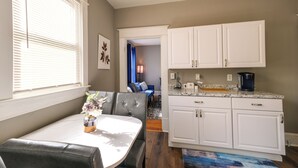 A dining area with a table and chairs, a kitchen with white cabinets, and a view into the living room. - Cozy Roanoke Vacation Rental: 2 Mi to Downtown! (Roanoke)