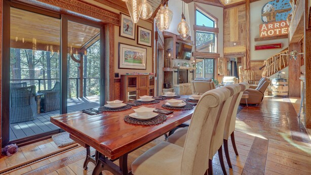 A spacious dining area with a wooden table set for six, surrounded by wicker chairs.