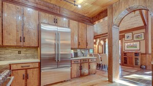 A spacious kitchen with wooden cabinets, a stainless steel refrigerator, and a dining area with a wooden table and chairs.