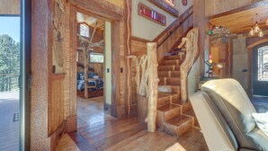 A wooden interior with a staircase, leather seating, and a view of the outdoors.