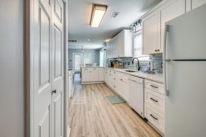 Una cocina moderna con armarios blancos, un refrigerador de acero inoxidable y piso de madera.