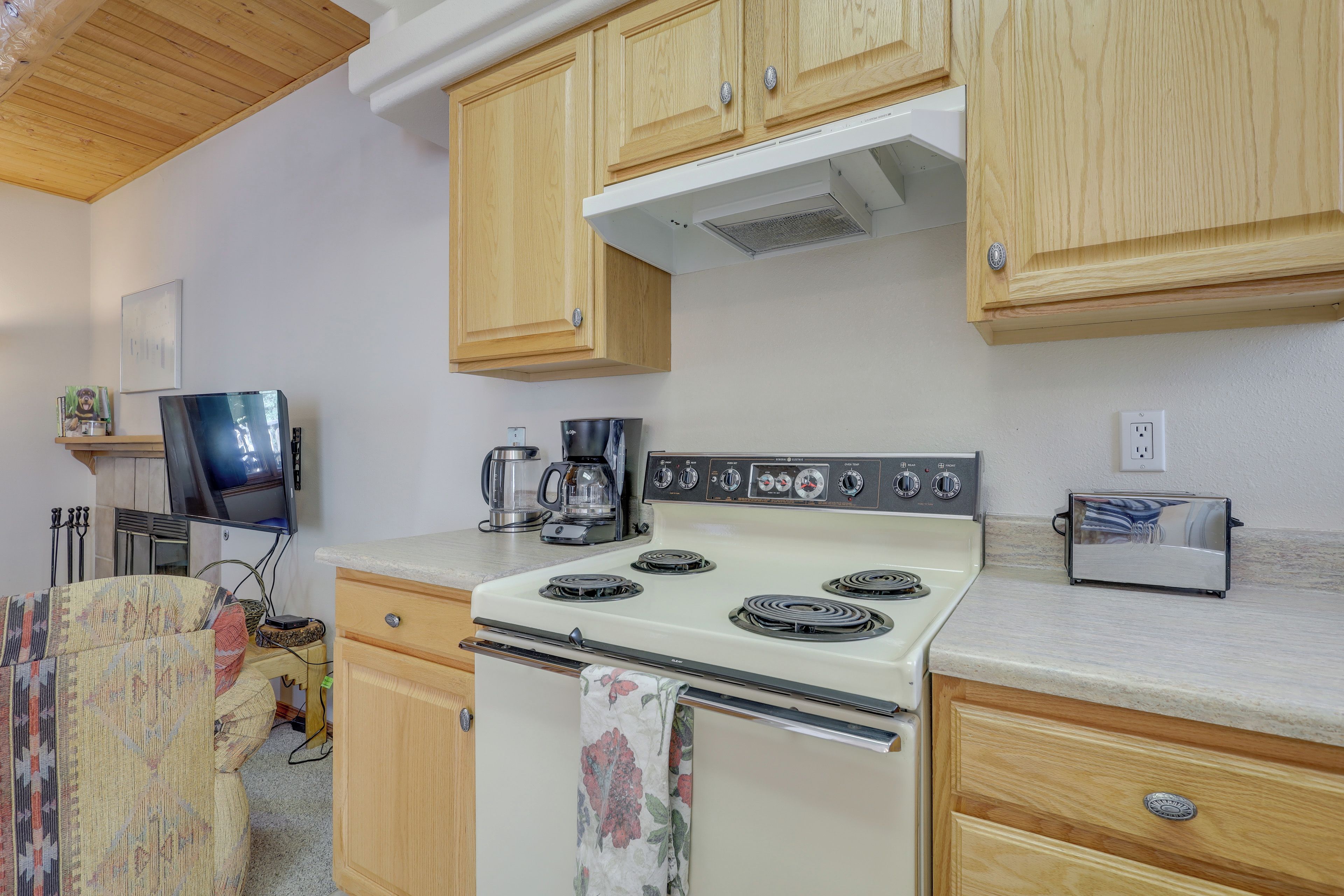 A compact kitchen with wooden cabinets, a white stove, a coffee maker, and a toaster.