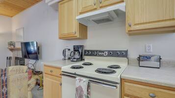 A compact kitchen with wooden cabinets, a white stove, a coffee maker, and a toaster.