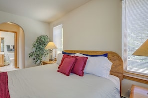 A neatly made bed with white and red pillows, a wooden headboard, and a bedside lamp. - Charming Amalia Retreat w/ Fireplace & Grill! (Amalia)