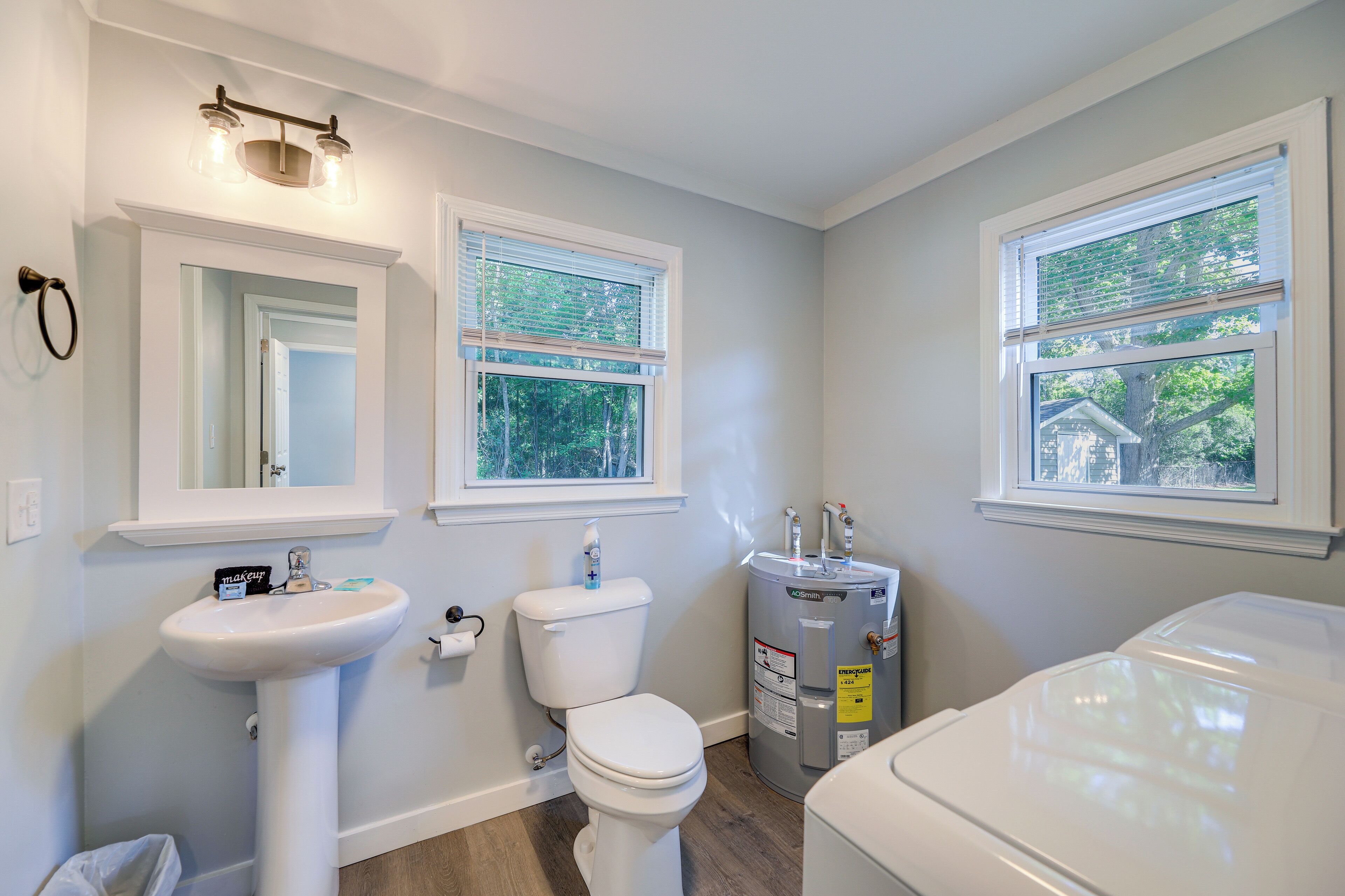 A bathroom with a sink, toilet, and window.