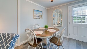 A dining area with a round table, white chairs, and a small potted plant. - New Bern Vacation Rental: Close to Neuse River! (New Bern)