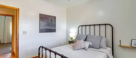 Un dormitorio con cama, ventilador de techo, mesita de noche y mesita auxiliar.