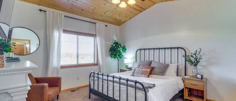 A bedroom with a bed, a nightstand, a chair, a ceiling fan, and a window with curtains.