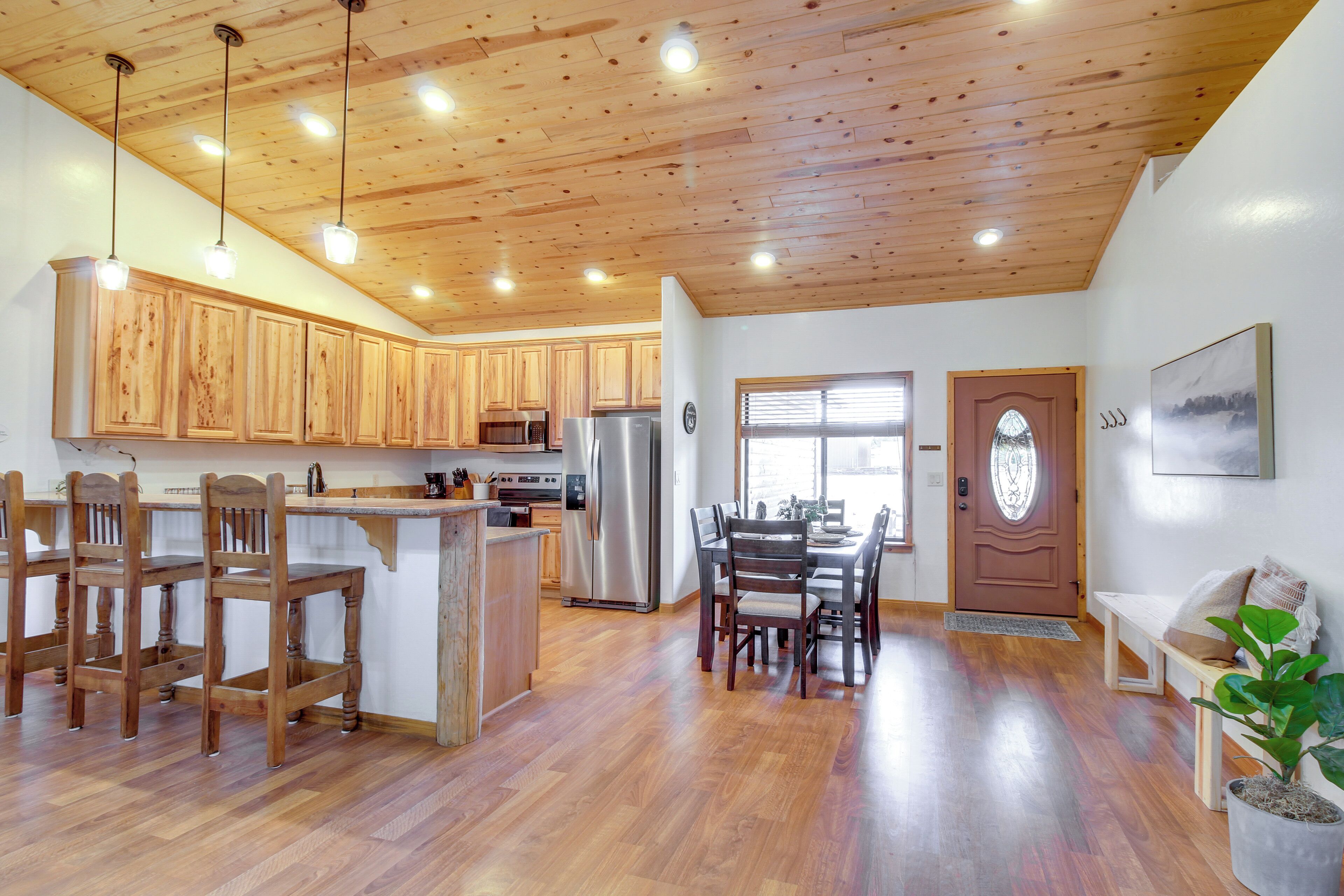 A spacious kitchen with wooden cabinets, a central island, and a dining area with chairs and a table.