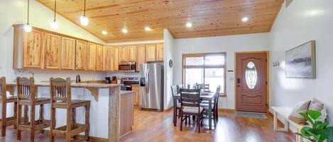 A spacious kitchen with wooden cabinets, a central island, and a dining area with chairs and a table.