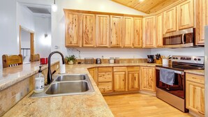 Una cocina con gabinetes de madera, electrodomésticos de acero inoxidable y encimera de granito.