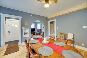 Comedor con mesa de madera, individuales rojos y ventilador de techo.