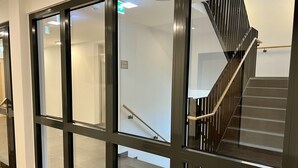 A modern interior with a glass partition, a staircase with a metal railing, and a sign indicating 'TRH WEST'. - AMH - Wohnen auf Zeit (Munich)
