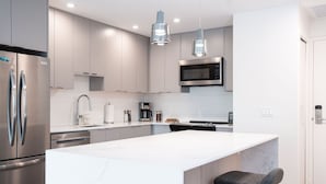 Una cocina moderna con electrodomésticos de acero inoxidable, una isla grande e iluminación colgante.