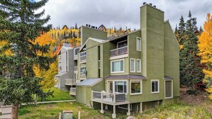 A multi-story building with balconies, a parking area, and autumn foliage in the background. - Snowy Peaks Haven | Walk to Slopes & Park (Brian Head)