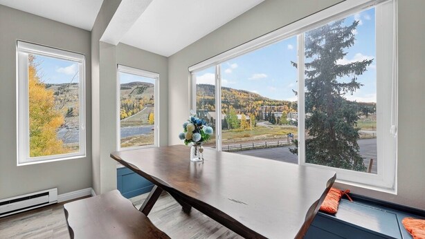 A modern kitchen with large windows, a wooden table, and a bench. - Snowy Peaks Haven | Walk to Slopes & Park (Brian Head)