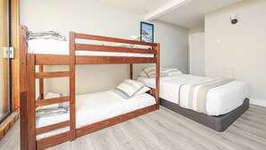 Habitación con literas de madera, la litera inferior con un almohadón y la litera superior con un almohadón y un cuadro enmarcado.