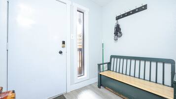 A room with a white door, a bench, a coat rack, and a window.