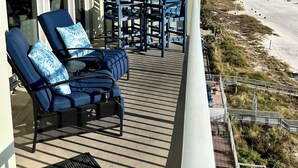 Un balcón con mobiliario exterior, vista a la playa y cielo despejado.