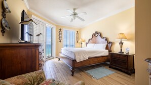 Un dormitorio con cama de madera, ventilador de techo, cómoda y mesita de noche con lámpara.