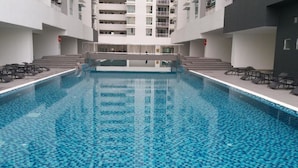 Una piscina interior con suelo de baldosas, rodeada de sillones de descanso y una escalera que lleva a plantas superiores.