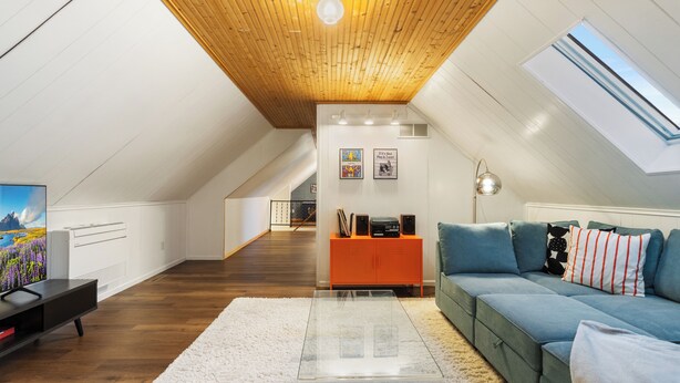 A modern loft bedroom with a sloped ceiling, a large window, a sofa, a coffee table, and a TV. - Shuffleboard - Gym - BBQ (Minneapolis)