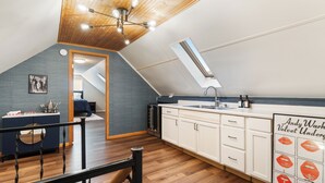 A modern kitchen with white cabinets, a black countertop, and a skylight. - Shuffleboard - Gym - BBQ (Minneapolis)