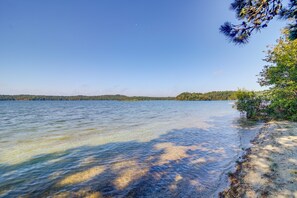 Kirkasvetinen järvi, jonka rannalla on hiekkaranta ja taustalla näkyy puita.