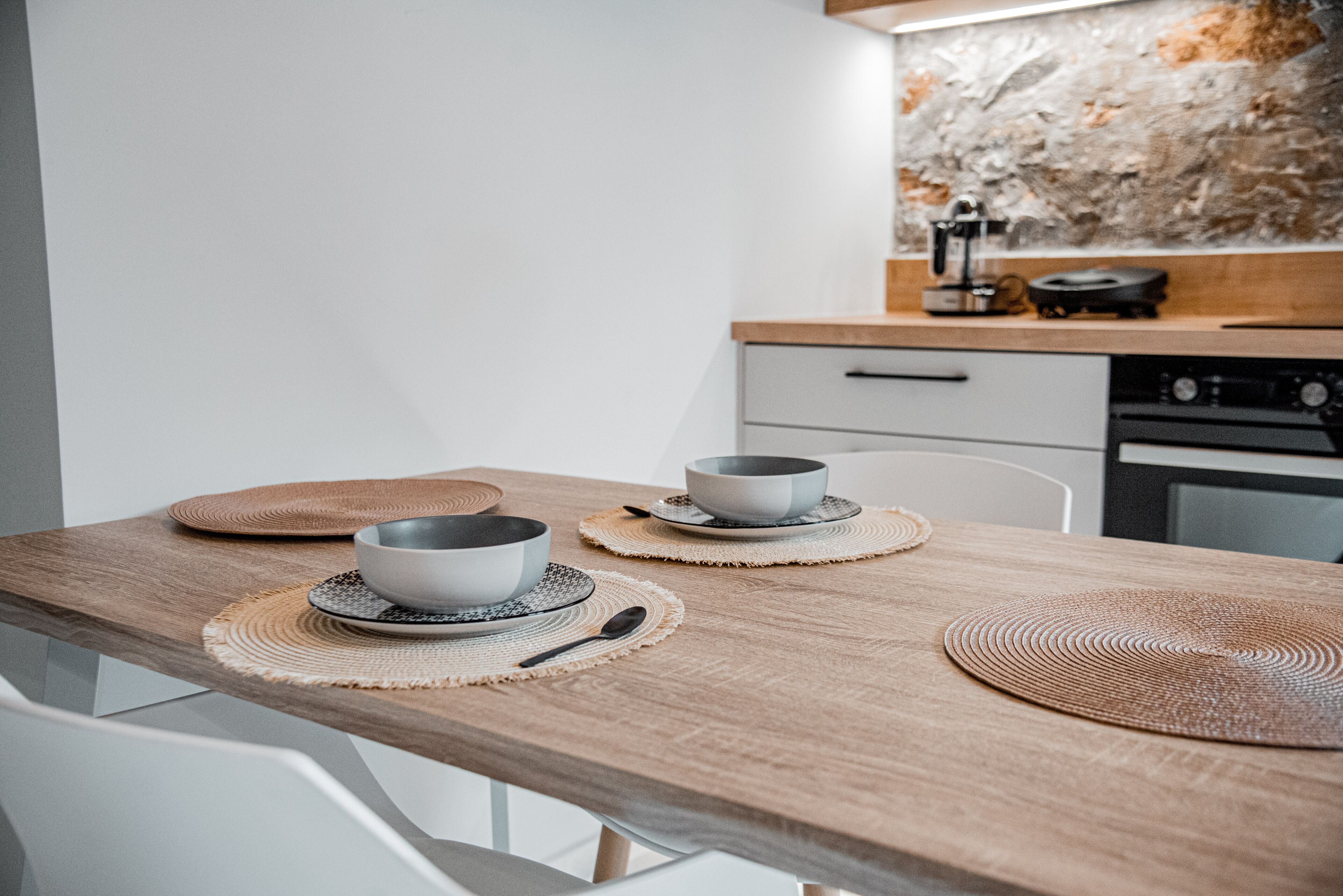 A modern kitchen with a wooden countertop, two bowls on placemats, and a coffee machine in the background.