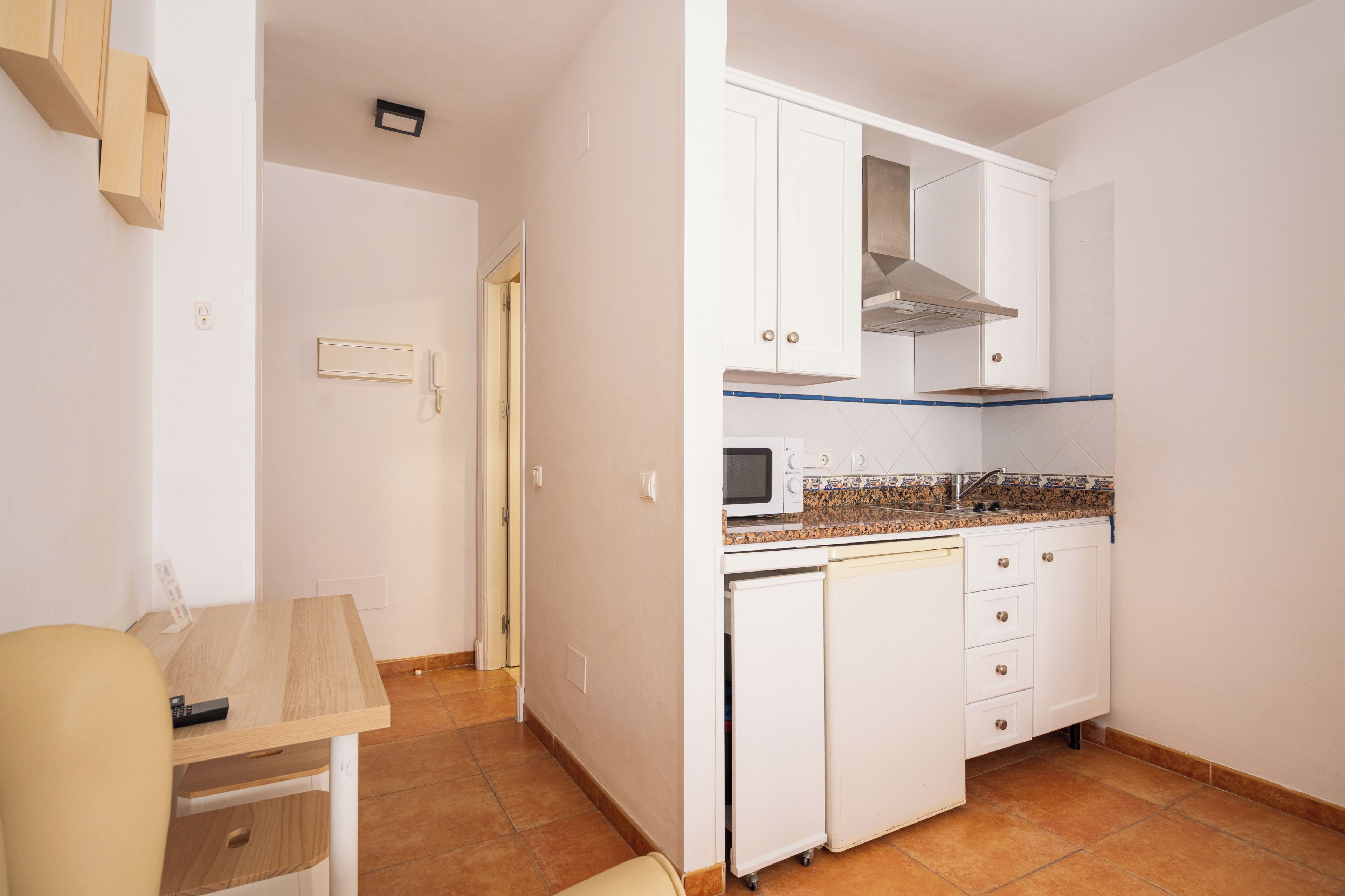 A kitchen with white cabinets, a microwave, and a small refrigerator.