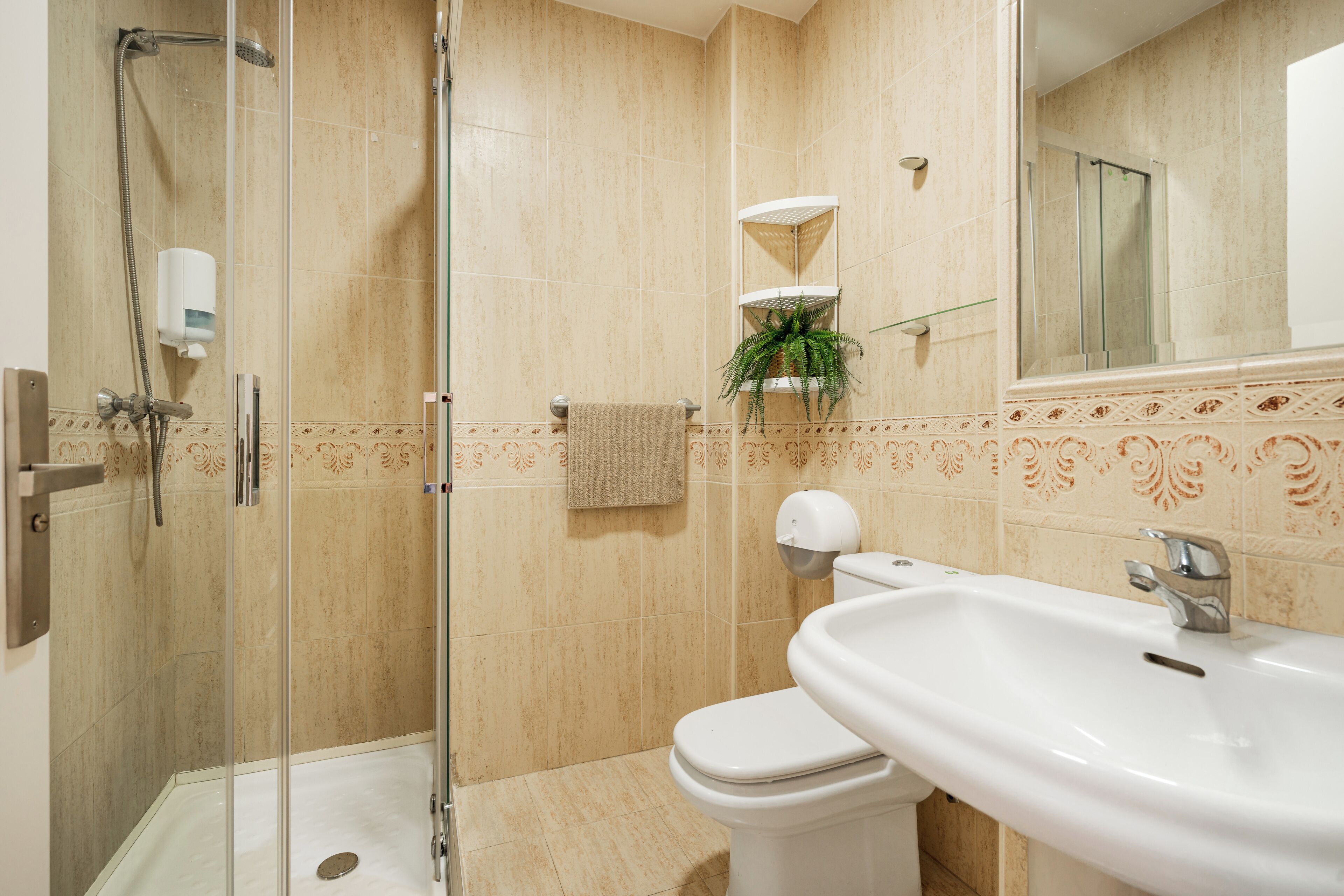 A bathroom with a glass-enclosed shower, a white sink, and a toilet.