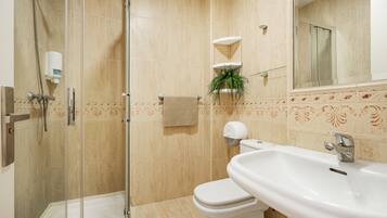 A bathroom with a glass-enclosed shower, a white sink, and a toilet.