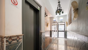 A hallway with a tiled floor, a door, and a wall-mounted sign. - Apartamentos Capricho del Mar (Torremolinos)