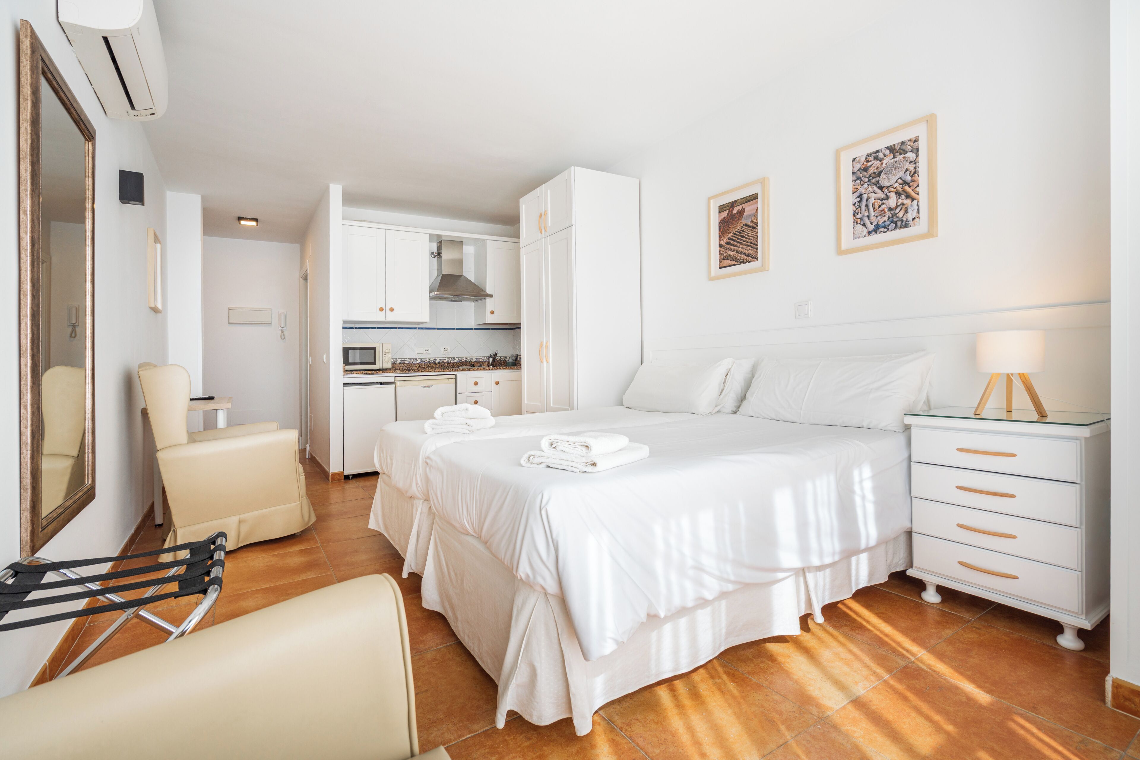 Een hotelkamer met twee bedden, een zithoek, een kitchenette en een badkamer.