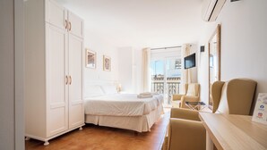 A hotel room with a bed, a desk, a chair, a TV, and a balcony with a railing. - Apartamentos Capricho del Mar (Torremolinos)