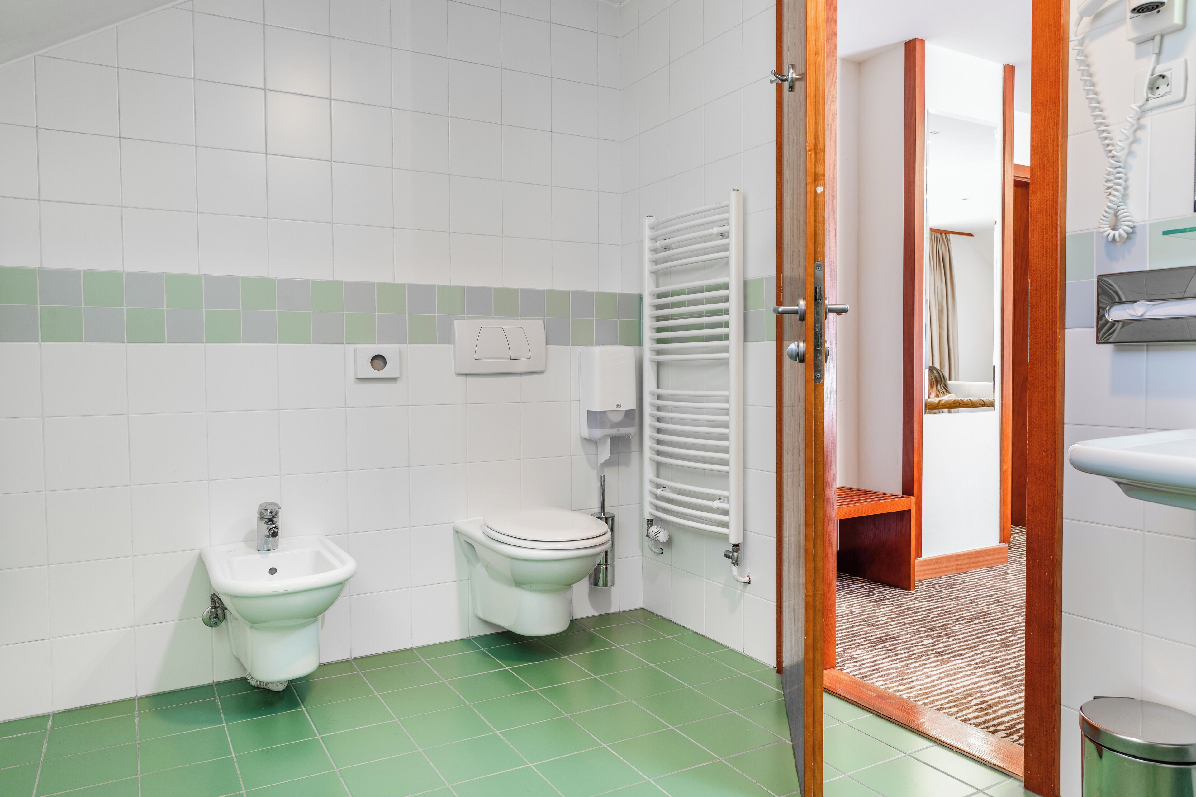 A bathroom with a bidet, toilet, and a towel rack.