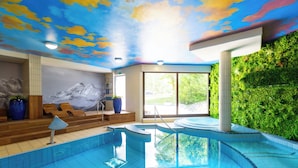 A swimming pool with a mountain mural, a green wall, and a view of the outdoors.