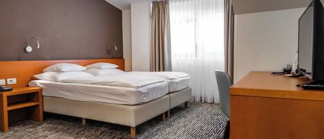Een hotelkamer met een bed, nachtkastje, televisie en bureau.