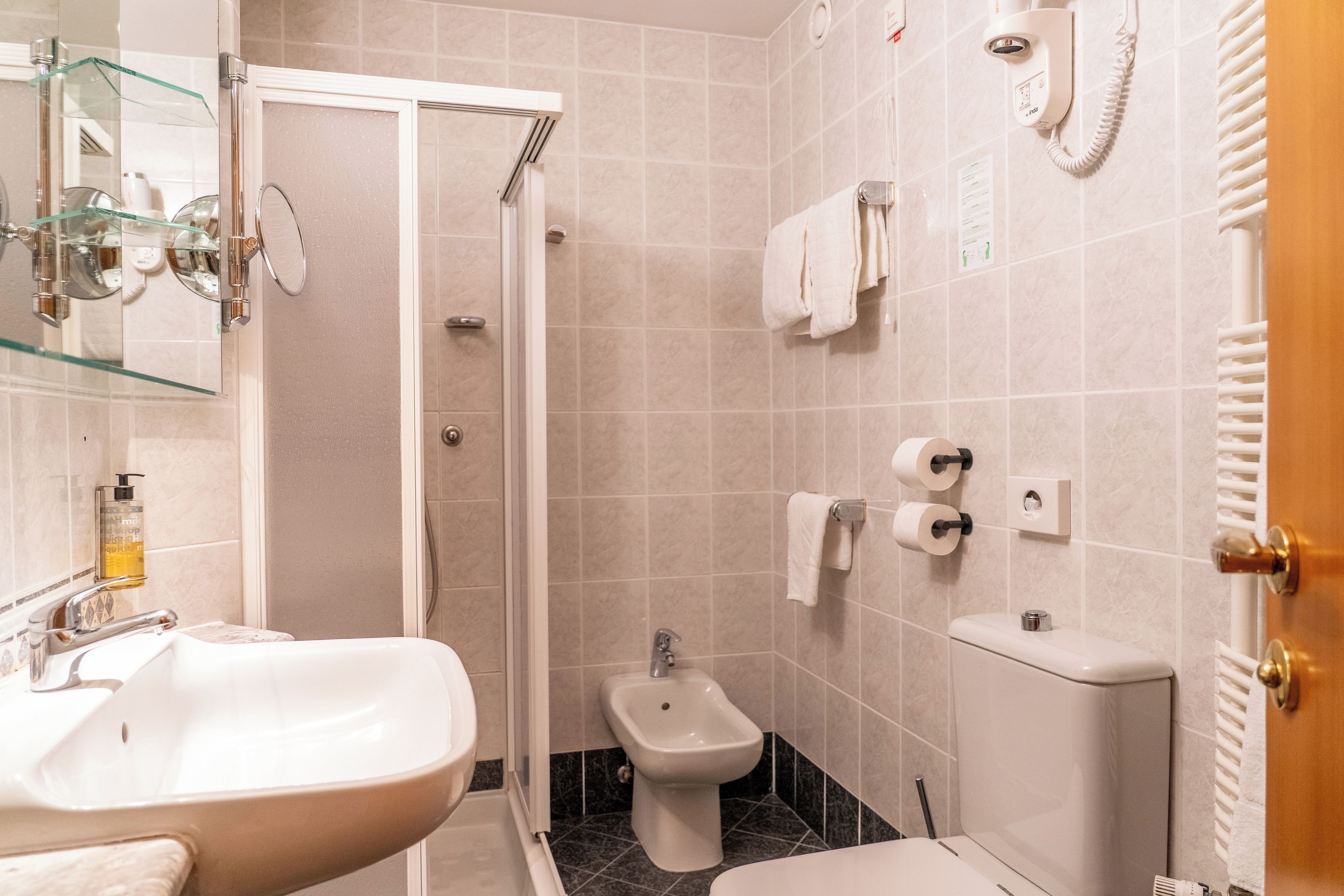 A bathroom with a sink, bidet, toilet, and a glass shower enclosure.