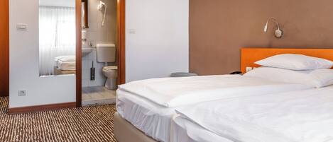 Habitación de hotel con cama, baño con inodoro y ducha.