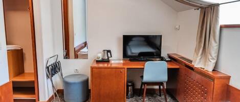 A hotel room with a bed, a desk, a chair, a television, and a wardrobe.