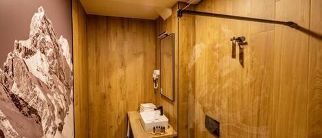 A wooden bathroom with a sink, mirror, and shower.