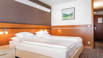Ein Hotelzimmer mit einem großen Bett, Nachttischen, einem Wandbild und einem Holz-Kopfteil.