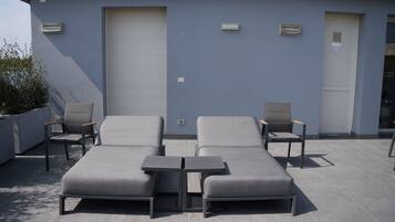 Una terraza en la azotea con dos sillones, una mesita y una planta en maceta.