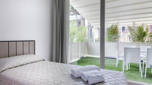 Un dormitorio con cama, un balcón con vistas a la ciudad y una mesa con sillas.