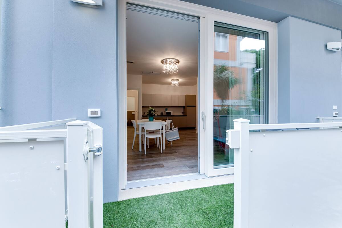 A modern apartment entrance with a sliding glass door leading to a dining area and kitchen.